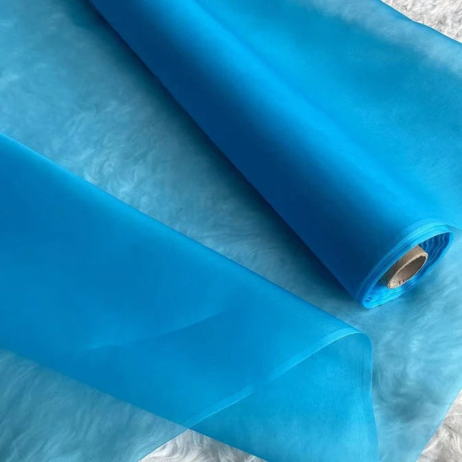 Un gros plan de l'Organza de soie multicolore 8 momme au mètre de Longan Craft France montre ce tissu lisse et translucide en pure soie de mûrier, parfait pour créer des robes luxueuses et disponible au mètre.