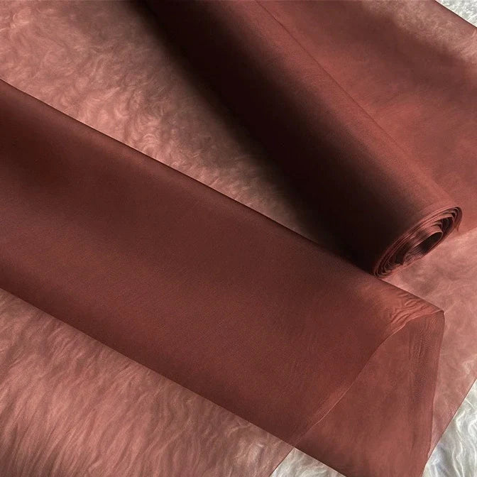 Deux rouleaux d'Organza de soie multicolore 8 momme de Longan Craft France sont déroulés, mettant en valeur la légèreté et la translucidité de la pure soie de mûrier - un tissu de luxe idéal pour les robes de soirée élégantes.