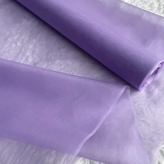 Un rouleau d'Organza de soie multicolore 8 momme au mètre de Longan Craft France est déroulé sur une surface blanche. Ce tissu de luxe en pure soie de mûrier est lisse, translucide et idéal pour les robes élégantes.