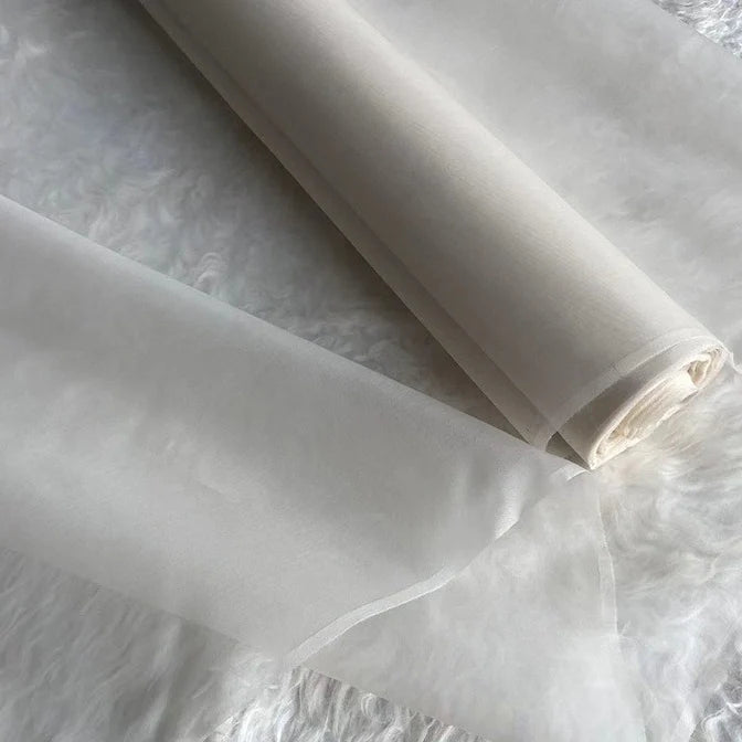 Deux rouleaux d'Organza de soie multicolore 8 momme de Longan Craft France, fabriqués à partir de pure soie de mûrier, sont présentés sur une surface blanche texturée. Ce tissu luxueux et léger est idéal pour les robes élégantes.