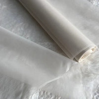 Deux rouleaux d'Organza de soie multicolore 8 momme de Longan Craft France, fabriqués à partir de pure soie de mûrier, sont présentés sur une surface blanche texturée. Ce tissu luxueux et léger est idéal pour les robes élégantes.