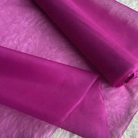 Deux rouleaux de Longan Craft France Organza de soie multicolore 8 momme sont partiellement déroulés, mettant en valeur la légèreté et la transparence de la pure soie de mûrier, idéale pour les robes de luxe.