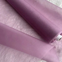Deux rouleaux d'Organza de soie multicolore 8 momme de Longan Craft France, fabriqués à partir de pure soie de mûrier, sont posés sur une surface blanche et douce. Le luxueux tissu de la robe est violet clair, légèrement translucide et élégant.