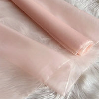 Deux rouleaux de Longan Craft France Organza de soie multicolore 8 momme, en pure soie de mûrier, sont présentés sur une surface blanche. Ce tissu luxueux et translucide a une texture lisse et une brillance élégante, idéale pour les robes.
