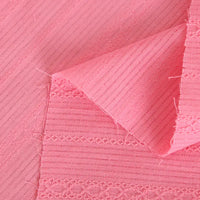 Vue détaillée du tissu dobby coton multicolore au mètre de Longan Craft France, montrant des rayures texturées et des broderies en rose, avec un coin plié pour révéler l'envers - le textile idéal pour des chemises confortables.