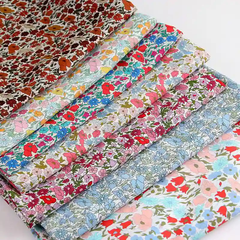 Une pile de Tissu linon de coton léger de Longan Craft France, idéal pour les projets de vêtements d'été, est soigneusement rangée. Ce tissu léger et vibrant est vendu au mètre et est parfait pour votre prochaine idée de couture créative.