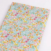 Le Tissu linon de coton léger au mètre de Longan Craft France présente un imprimé floral multicolore avec des fleurs roses, jaunes, orange et rouges ainsi que des feuilles vertes sur fond blanc - parfait pour les vêtements d'été.