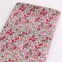 Le Longan Craft France Tissu linon de coton léger au mètre présente un imprimé floral multicolore sur fond blanc, idéal pour la confection de vêtements d'été.