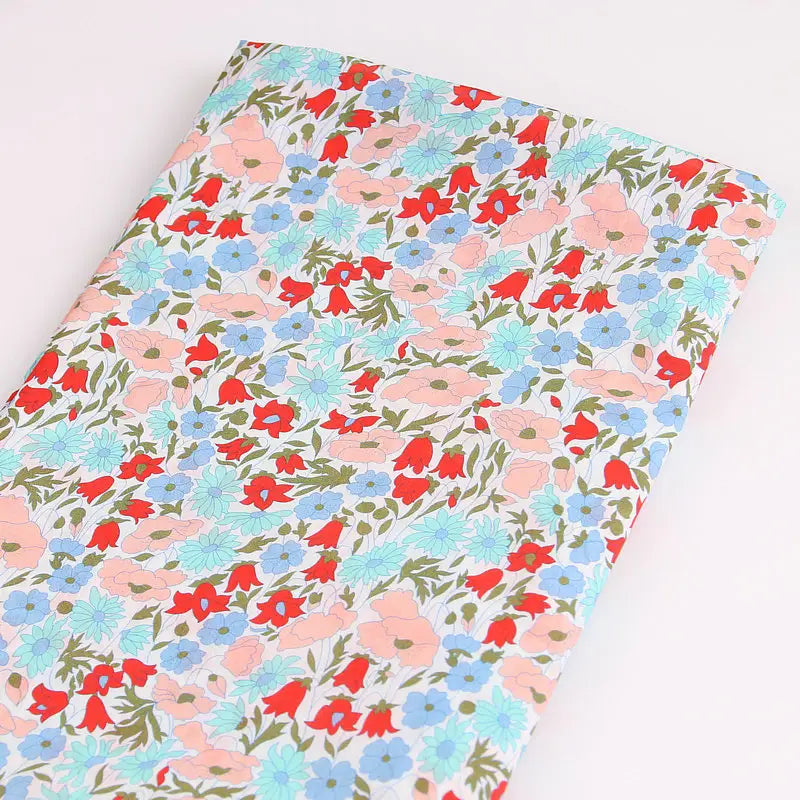 Le Tissu linon de coton léger au mètre de Longan Craft France présente un imprimé floral multicolore sur fond blanc et est idéal pour les vêtements d'été élégants et aérés.