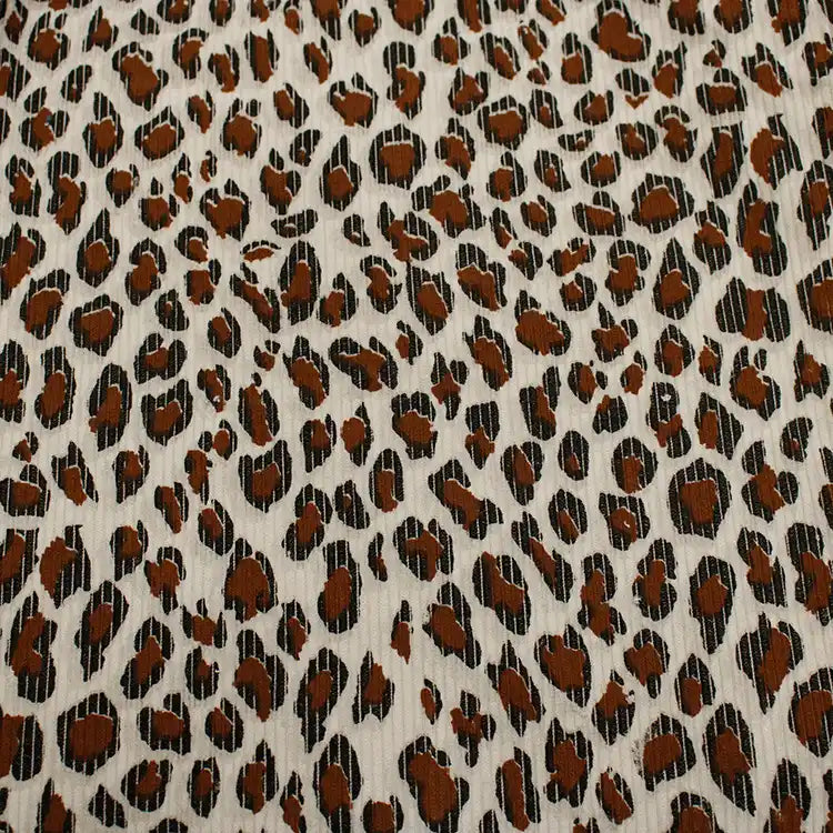 Gros plan sur le tissu côtelé imprimé léopard multicolore au mètre de Longan Craft France, un velours de polyester doux à l'imprimé animalier, avec des taches brunes et noires irrégulières sur un fond beige clair, idéal pour l'habillement.