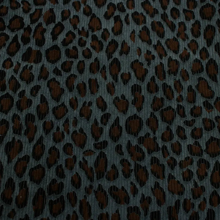 Gros plan sur le tissu côtelé imprimé léopard multicolore de Longan Craft France au mètre : velours côtelé polyester doux, aux motifs animaliers noirs et marron se détachant sur fond sombre, idéal pour vêtements.