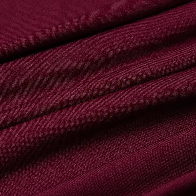 Gros plan sur un tissu jersey multicolore en polyester et élasthanne de Longan Craft France, vendu au mètre, qui présente un tissage fin, une légère brillance et une texture visible avec des plis horizontaux - idéal pour les robes.