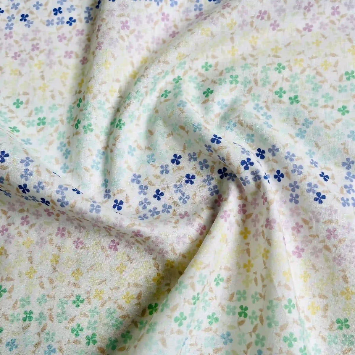 Le Linon de coton imprimé multicolore au mètre de Longan Craft France présente un imprimé floral doux avec des fleurs bleues, jaunes, vertes et violettes sur un fond clair. Ce tissu linon de coton à fleurs se drape magnifiquement grâce à de légers plis.