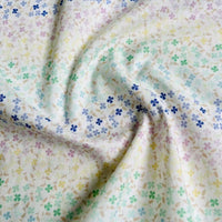 Le Linon de coton imprimé multicolore au mètre de Longan Craft France présente un imprimé floral doux avec des fleurs bleues, jaunes, vertes et violettes sur un fond clair. Ce tissu linon de coton à fleurs se drape magnifiquement grâce à de légers plis.