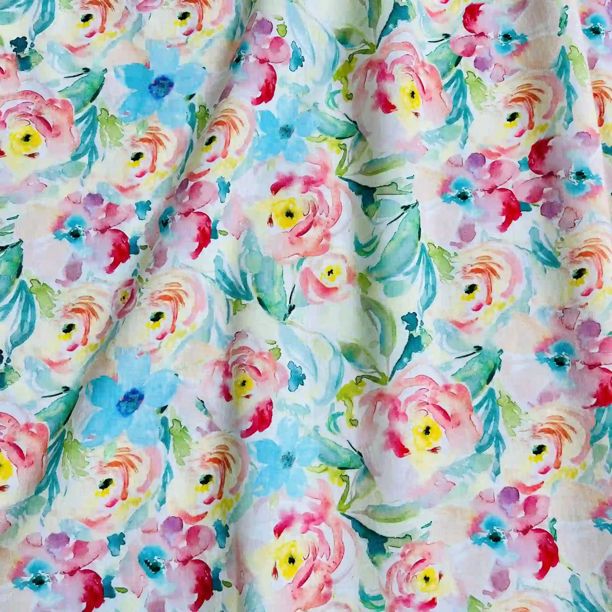 Linon de coton imprimé multicolore au mètre de Longan Craft France : tissu linon doux à fleurs aquarelle roses, jaunes et bleues avec feuilles vertes sur fond blanc, légèrement froissé.