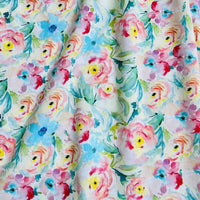 Linon de coton imprimé multicolore au mètre de Longan Craft France : tissu linon doux à fleurs aquarelle roses, jaunes et bleues avec feuilles vertes sur fond blanc, légèrement froissé.