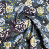 Gros plan sur le Linon de coton imprimé multicolore au mètre de Longan Craft France, qui présente un motif floral tourbillonnant doux et légèrement brillant en bleu, blanc et jaune sur un fond sombre.