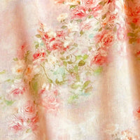 Un gros plan de Linon de coton imprimé multicolore au mètre de Longan Craft France montre de douces roses et pêches de style aquarelle avec des feuilles vertes sur un fond pastel - un tissu linon de coton à fleurs délicat.