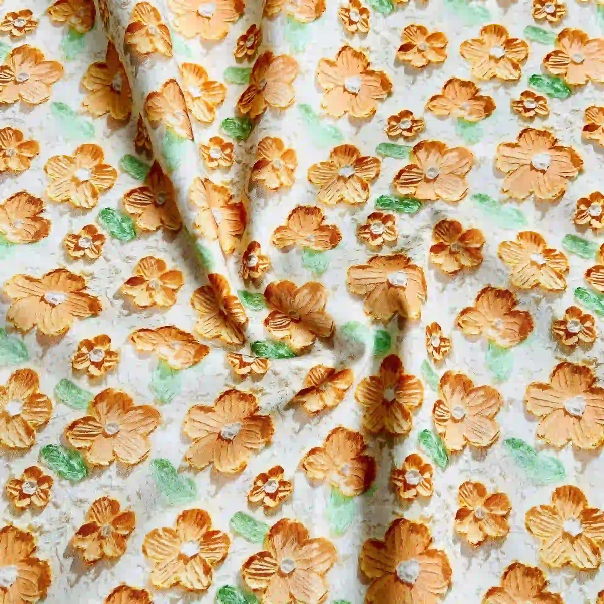 Découvrez le Linon de coton imprimé multicolore au mètre de Longan Craft France : un tissu floral en coton doux avec des fleurs orange et jaunes et des feuilles vertes sur fond blanc, légèrement froissé pour ajouter de la texture et de la dimension.