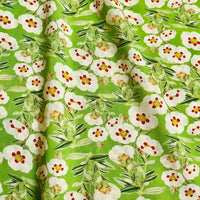 Linon de coton imprimé multicolore au mètre de Longan Craft France : tissu linon doux à fleurs, fond vert lumineux avec motifs floraux blancs à cœur rouge et feuillage, idéal pour vos créations florales raffinées.