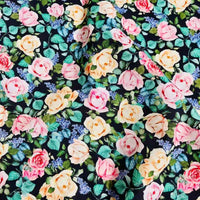 Le linon de coton imprimé multicolore au mètre de Longan Craft France présente des roses roses, jaunes et pêche, des feuilles vertes et de petites fleurs violettes sur fond sombre. Tissu doux idéal pour vos créations florales.