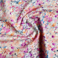 Gros plan sur Linon de coton imprimé multicolore au mètre de Longan Craft France, un tissu doux en coton linon avec un motif floral abstrait en rose, violet, orange et bleu, artistiquement rassemblé dans un tourbillon.