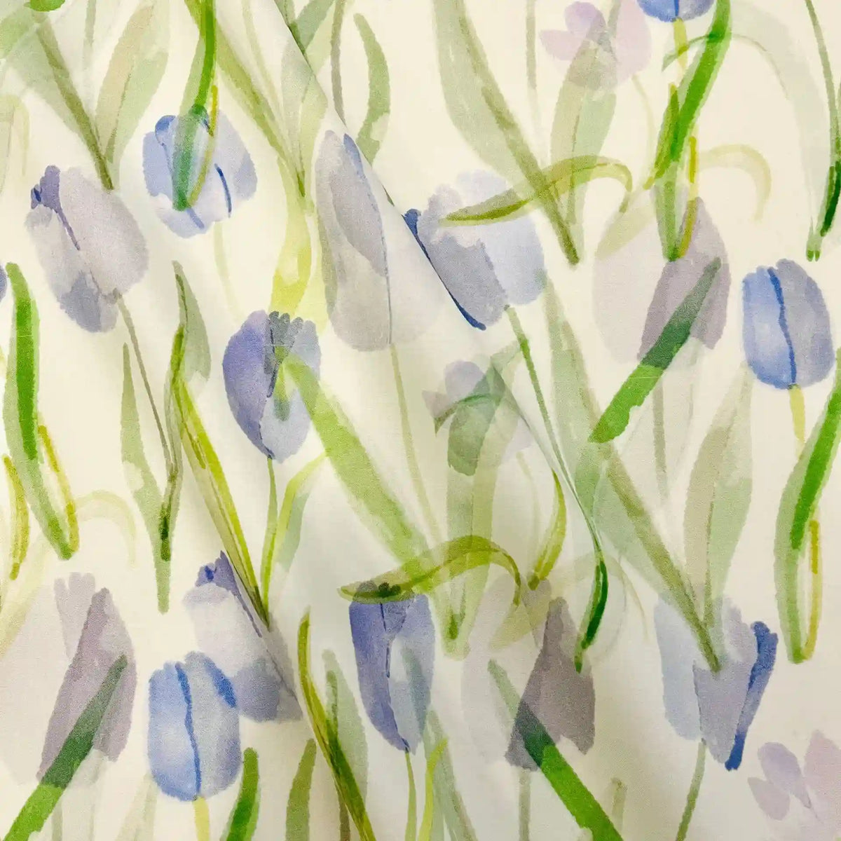 Gros plan sur le Linon de coton imprimé multicolore au mètre de Longan Craft France, montrant un motif floral de style aquarelle avec des tulipes violettes et des feuilles vertes sur un linon de coton blanc doux.