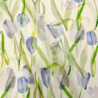 Gros plan sur le Linon de coton imprimé multicolore au mètre de Longan Craft France, montrant un motif floral de style aquarelle avec des tulipes violettes et des feuilles vertes sur un linon de coton blanc doux.