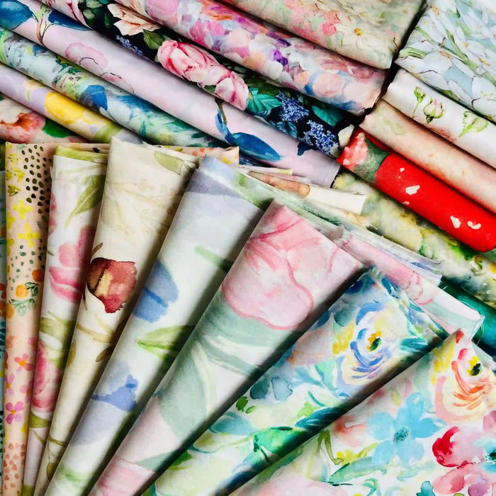 Linon de coton imprimé multicolore au mètre de Longan Craft France, un tissu floral doux, est présenté plié et empilé, mettant en valeur ses motifs floraux pastels et vibrants.