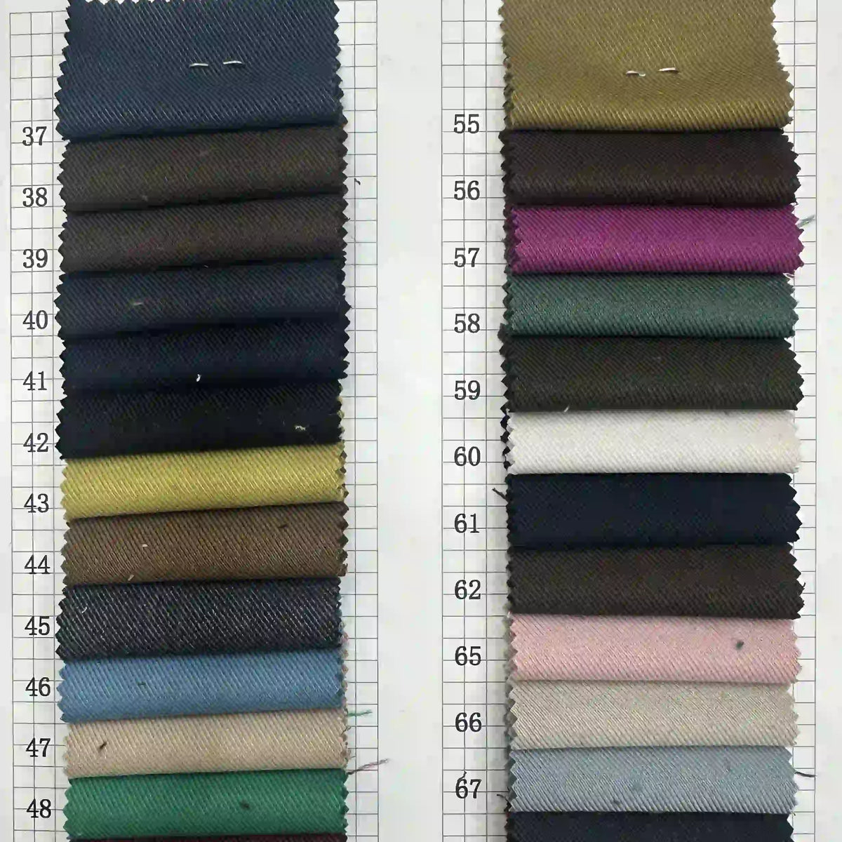 Deux colonnes de Tissu gabardine stretch multicolore au mètre de Longan Craft France sont disposées sur une grille blanche numérotée 37-67. Ce tissu en viscose offre des bleus, des verts, des bruns, des roses et des neutres - idéal pour les costumes ajustés ou les uniformes sur mesure.
