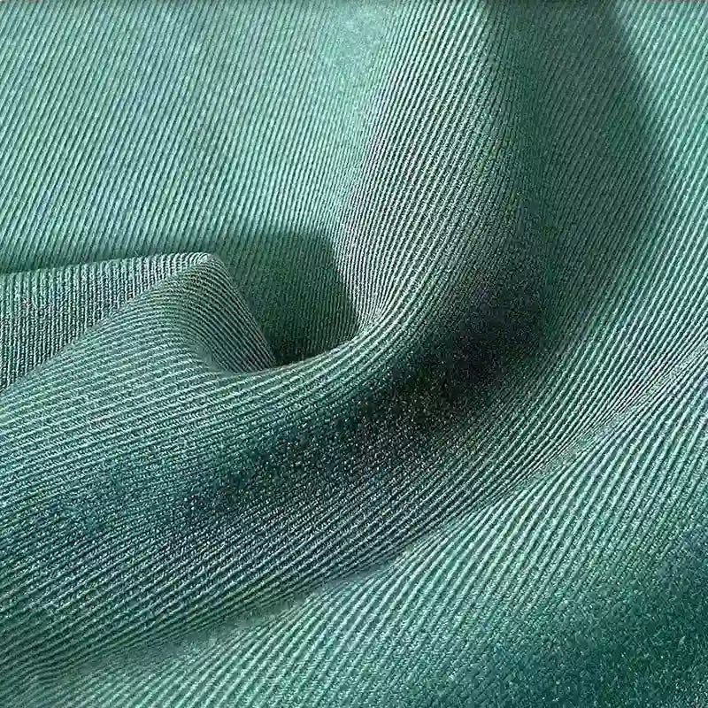 Gros plan sur le Tissu gabardine stretch multicolore au mètre de Longan Craft France, montrant sa texture de viscose tissée bleu-vert clair avec des stries diagonales visibles - parfait pour les costumes ajustés et les uniformes sur mesure.