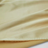 Un gros plan montre la texture lisse, légèrement brillante et le bord non fini du tissu satin polyester multicolore de Longan Craft France, parfait pour l'habillement, disponible au mètre.