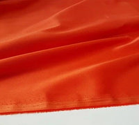 Un gros plan du tissu en satin multicolore au mètre de Longan Craft France montre un polyester lisse et brillant avec un bord cousu visible, idéal pour les vêtements et disponible au mètre.