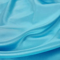 Gros plan sur un tissu en satin bleu clair, lisse et brillant, de Longan Craft France, un tissu en satin de polyester multicolore idéal pour l'habillement, montrant de légers plis et de douces rides sur sa surface.
