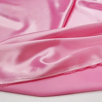 Gros plan sur le tissu lisse et brillant en satin multicolore au mètre de Longan Craft France, légèrement froissé et doux avec une brillance visible - idéal tissu satin polyester soyeux pour vêtements.