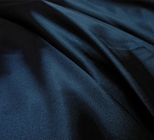 Gros plan sur le tissu de polyester satiné multicolore de Longan Craft France, montrant sa texture lisse, son éclat subtil et ses plis doux, idéaux pour les vêtements.