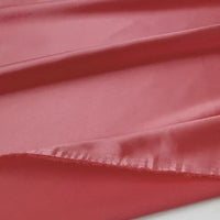 Gros plan sur le tissu en satin multicolore au mètre de Longan Craft France, un satin de polyester lisse et soyeux idéal pour l'habillement, avec des plis doux, une légère brillance et un bord brut non fini.