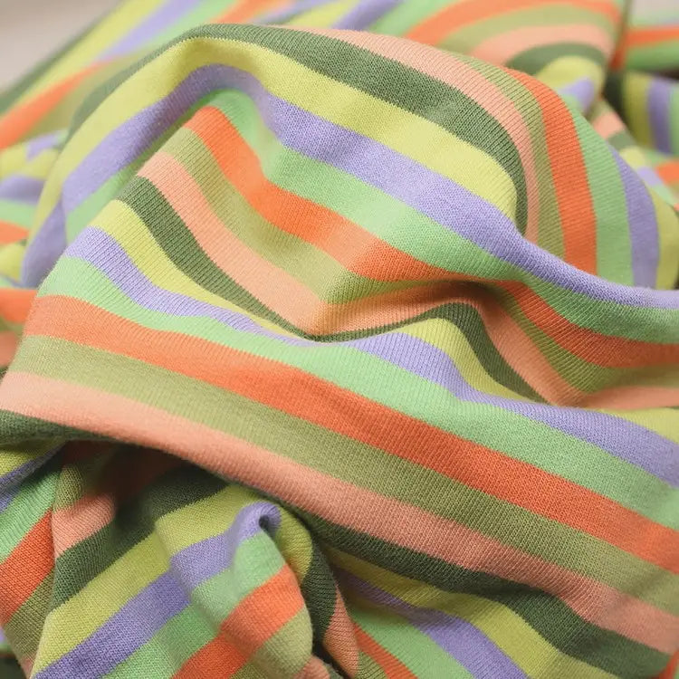 Gros plan sur le tissu French Terry coton à rayures multicolores pastel (vert, orange clair, pêche, lavande) de Longan Craft France, un tissu extensible et chaud vendu au mètre, idéal pour des sweatshirts cosy.