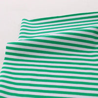 Gros plan sur le tissu jersey coton rayé multicolore de Longan Craft France, qui présente des rayures horizontales vertes et blanches. Ce jersey au mètre extensible, idéal pour les vêtements de sport, est présenté légèrement plié sur un fond clair.