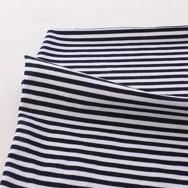 Gros plan sur le Tissu jersey coton rayé multicolore au mètre de Longan Craft France, un tissu extensible en jersey de coton et d'élasthanne pour les vêtements de sport, soigneusement plié sur une surface claire.