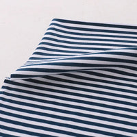 Gros plan sur le tissu jersey coton rayé multicolore au mètre de Longan Craft France, un tissu jersey de coton extensible pour vêtements de sport, avec des rayures horizontales bleu marine et blanches, soigneusement plié sur une surface claire.