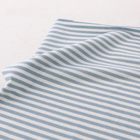 Un morceau de tissu Longan Craft France tissu jersey coton rayé multicolore au mètre, un jersey coton élasthanne doux et extensible pour vêtements de sport, avec des rayures horizontales, est posé à plat sur une surface légère avec un léger pli près d'un bord.