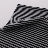 Un morceau de "Tissu jersey coton rayé multicolore au mètre" de Longan Craft France, un tissu extensible en jersey de coton pour vêtements de sport, est présenté à plat avec un coin plié sur une surface blanche.
