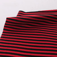 Un morceau de Tissu jersey coton rayé multicolore au mètre de Longan Craft France, un jersey de coton extensible pour vêtements de sport, avec des rayures horizontales noires et rouges régulièrement espacées, est posé sur une surface blanche et légèrement plié dans le coin supérieur gauche.