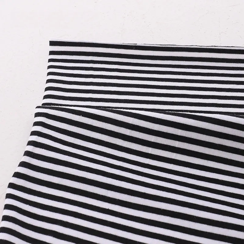 Gros plan sur le Tissu jersey coton rayé multicolore au mètre de Longan Craft France, montrant des rayures horizontales et une section pliée pour montrer l'alignement. Jersey coton élasthanne extensible pour vêtements de sport sur fond clair uni.