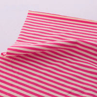 Un morceau de Tissu jersey coton rayé multicolore au mètre de Longan Craft France est présenté, avec un coin soulevé pour montrer le tissu jersey coton-élasthanne doux et extensible et ses rayures vibrantes - parfait pour les vêtements de sport.