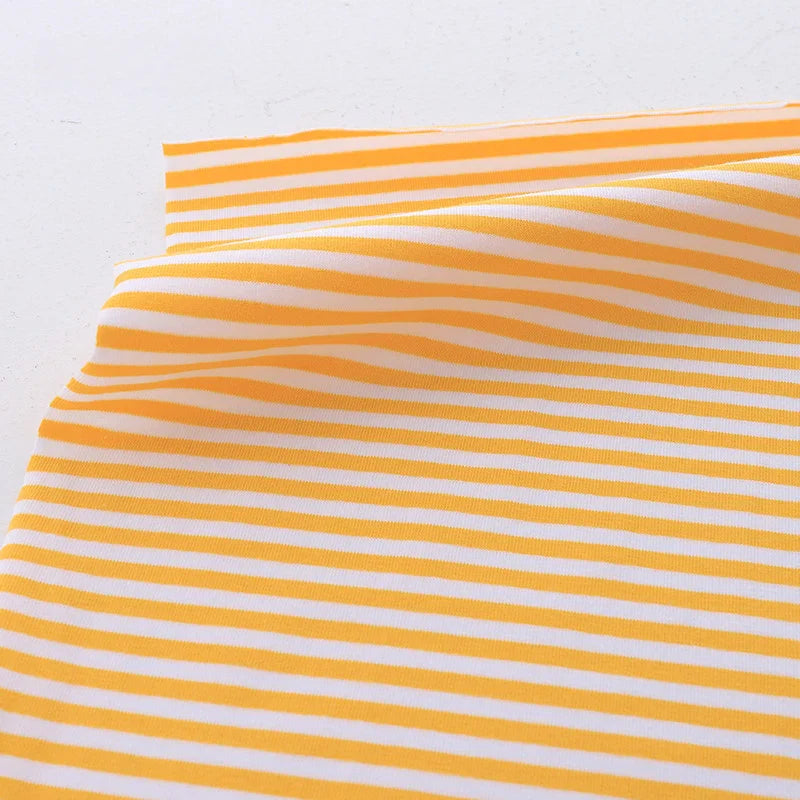 Un morceau de Tissu jersey coton rayé multicolore au mètre de Longan Craft France, parfait pour les vêtements de sport, avec des rayures horizontales jaunes et blanches est légèrement plié sur une surface plane.
