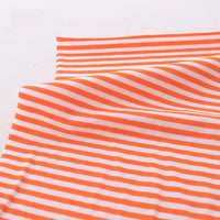 Un morceau de Tissu jersey coton rayé multicolore de Longan Craft France, au mètre, extensible en coton élasthanne, est étalé sur une surface blanche. Le tissu est partiellement plié, affichant des rayures sportives orange et blanches.