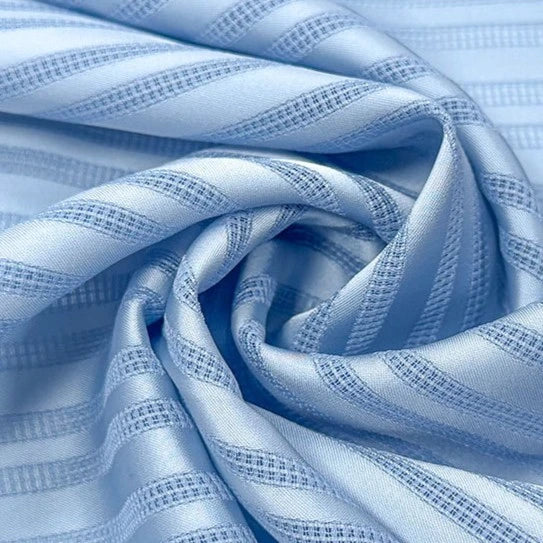 Gros plan sur le tissu dobby rayé multicolore en polyester au mètre de Longan Craft France, montrant une alternance de rayures lisses et texturées d'un bleu clair brillant. Ce tissu chemise dobby aéré est parfait pour réaliser des vêtements doux et élégants.