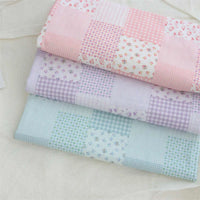 Trois patchworks pliés en tissu popeline de coton Longan Craft France sont empilés : le haut est rose avec des motifs floraux et à carreaux pastel, le milieu est lavande, et le bas est bleu clair avec des carrés floraux et à carreaux bleus de style Vichy.